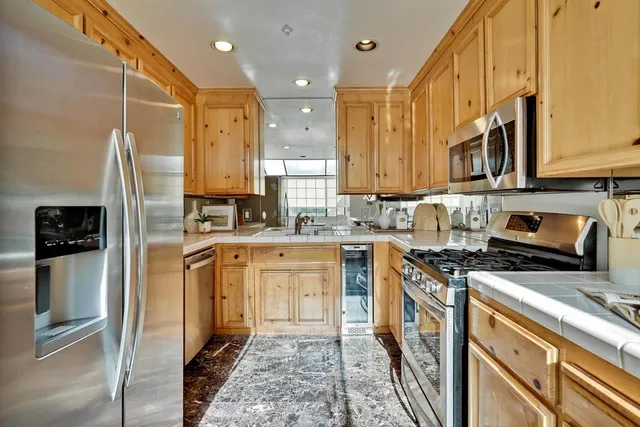 a kitchen with stainless steel appliances granite countertop a refrigerator a stove and a sink