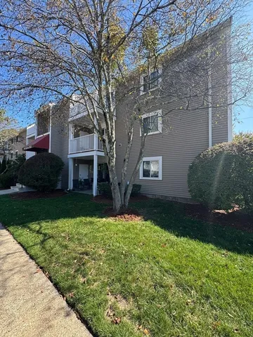 a view of a yard in front of a brick house with plants and large trees