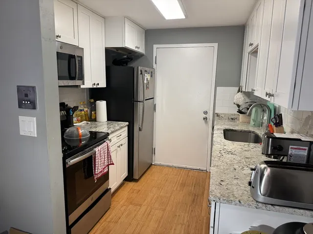 a kitchen with stainless steel appliances granite countertop a refrigerator a stove and a sink