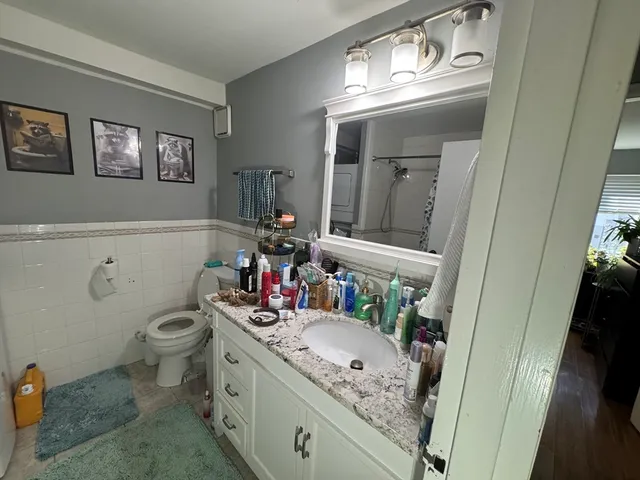 a bathroom with a granite countertop sink a toilet and a mirror