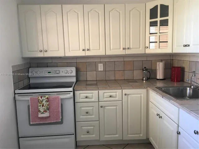 a kitchen with white cabinets and sink