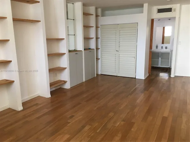 a view of empty room with wooden floor and cabinet