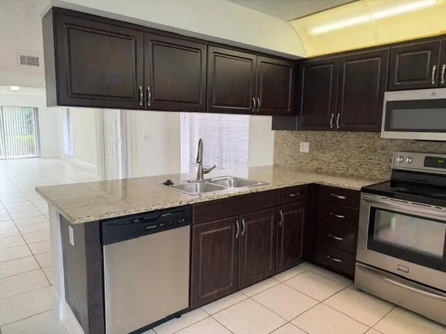 a kitchen with stainless steel appliances granite countertop wooden cabinets a stove top oven a sink and dishwasher