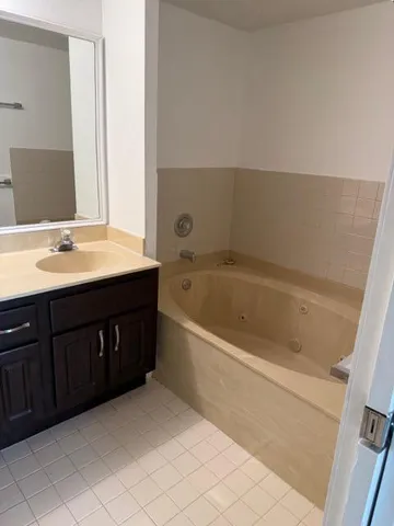 a spacious bathroom with a bathtub sink and mirror