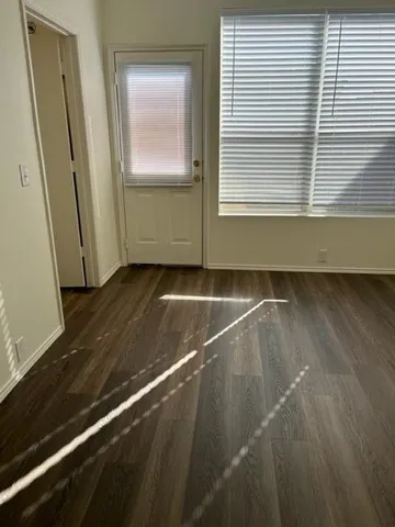 a view of an empty room with wooden floor and a window