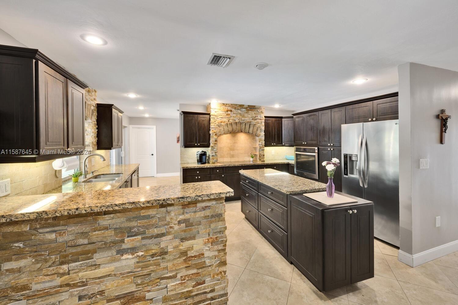18565 Southwest 295th Terrace Homestead, FL 33030 - Photo 20 of 42 a kitchen with granite countertop a refrigerator and a stove top oven