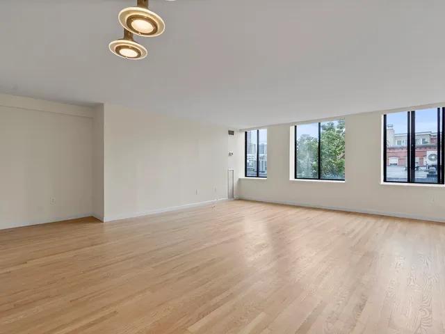 a view of an empty room with wooden floor and windows