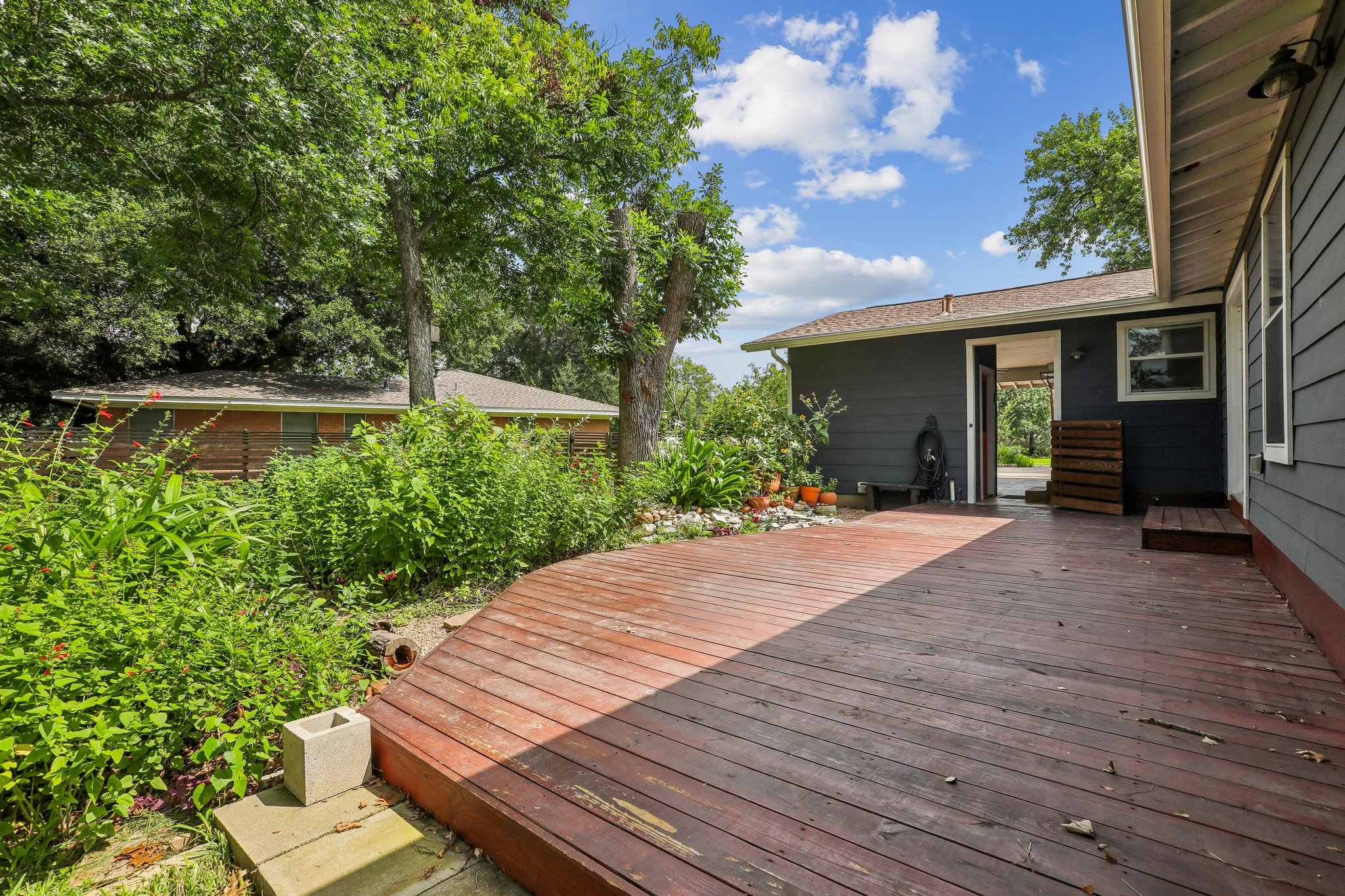 1114 West 2nd Street Elgin, TX 78621 - Photo 23 of 31 A spacious wooden deck extends into a lush, green garden, perfect for outdoor relaxation.