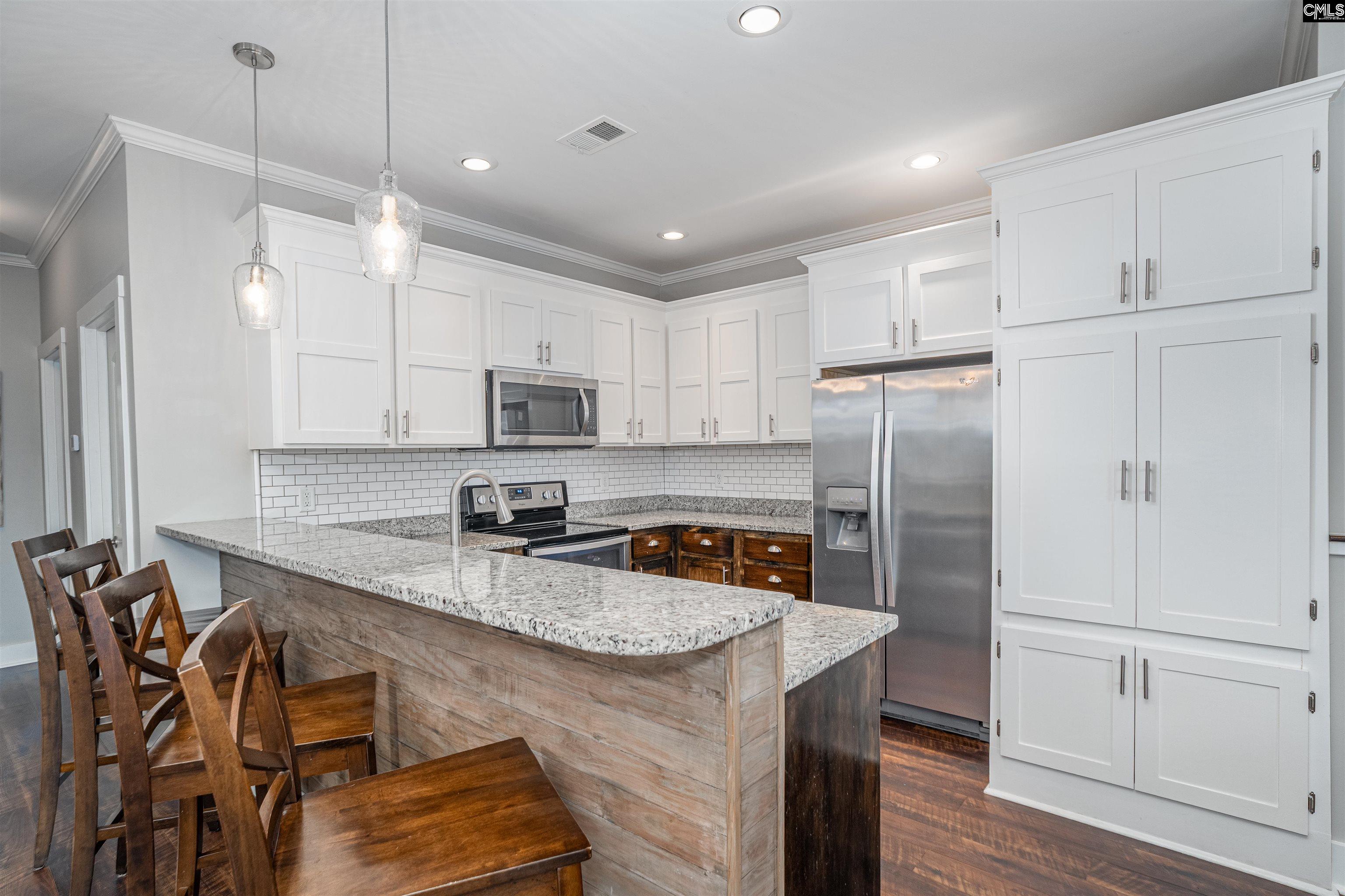 649 Sandbar Road Chapin, SC 29036 - Photo 10 of 40 a kitchen with stainless steel appliances granite countertop a refrigerator a sink dishwasher a stove and white cabinets with wooden floor