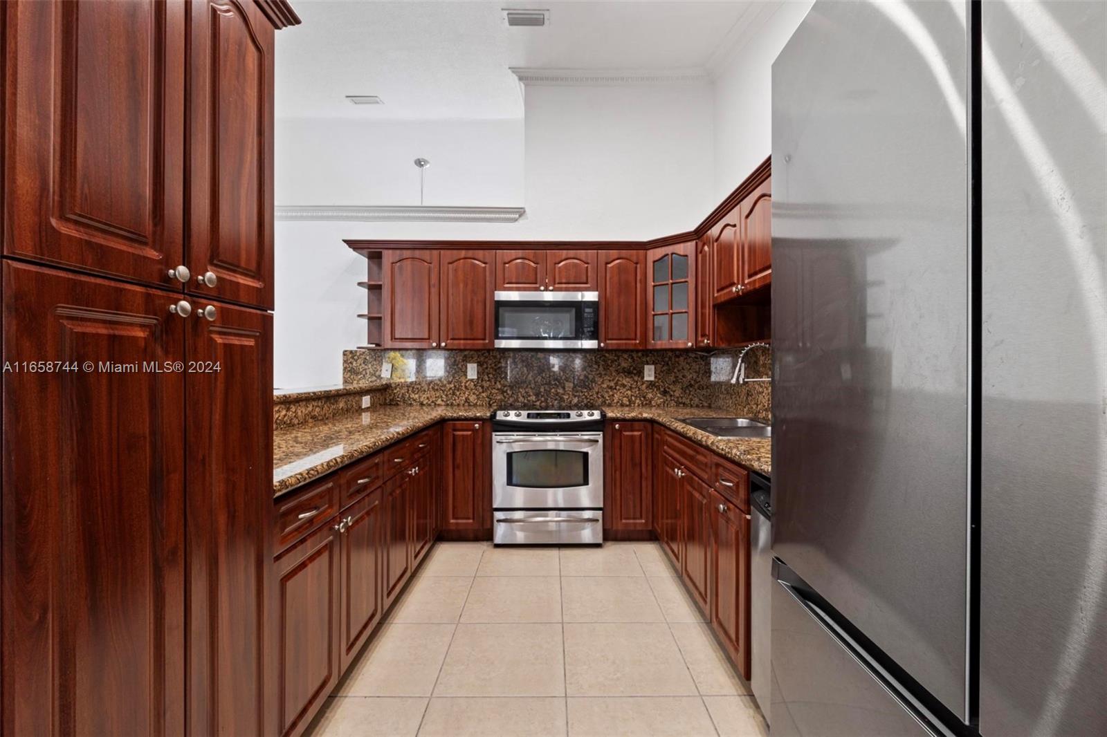 3209 Southwest 142nd Place Miami, FL 33175 - Photo 12 of 42 a kitchen with stainless steel appliances granite countertop a refrigerator and a stove top oven