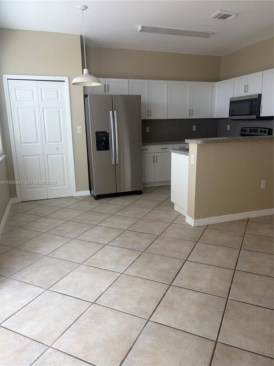 12398 Southwest 125th Terrace Miami, FL 33186 - Photo 3 of 45 a kitchen with granite countertop a refrigerator and a stove top oven
