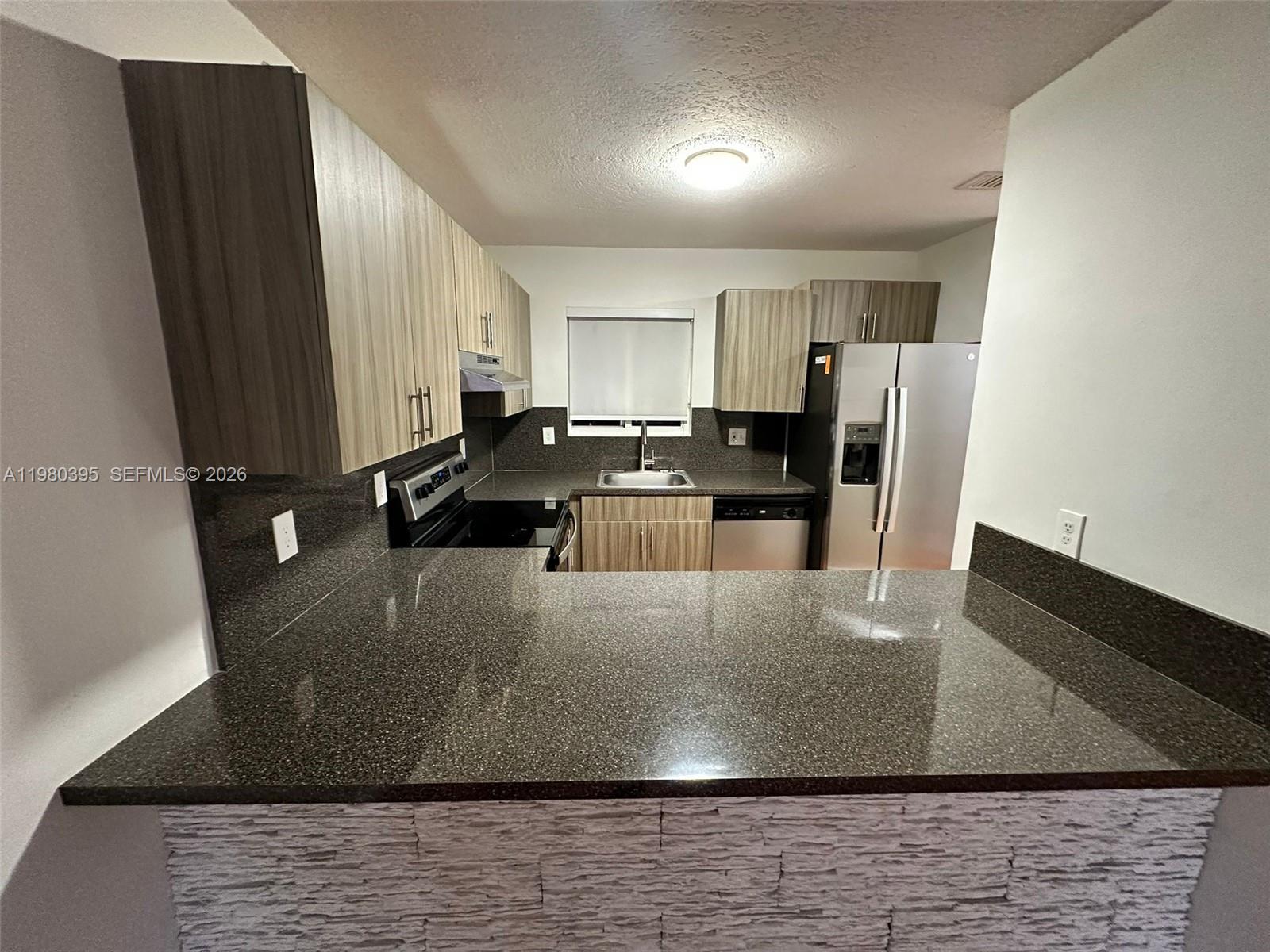 6235 Southwest Kendale Lakes Circle, Unit 237 Miami, FL 33183 - Photo 1 of 24 a view of a kitchen with kitchen island a sink wooden floor and a refrigerator