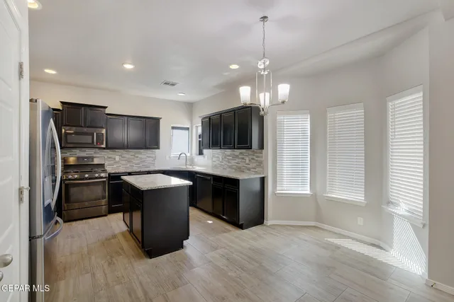 a large kitchen with kitchen island granite countertop stainless steel appliances and a view of living room