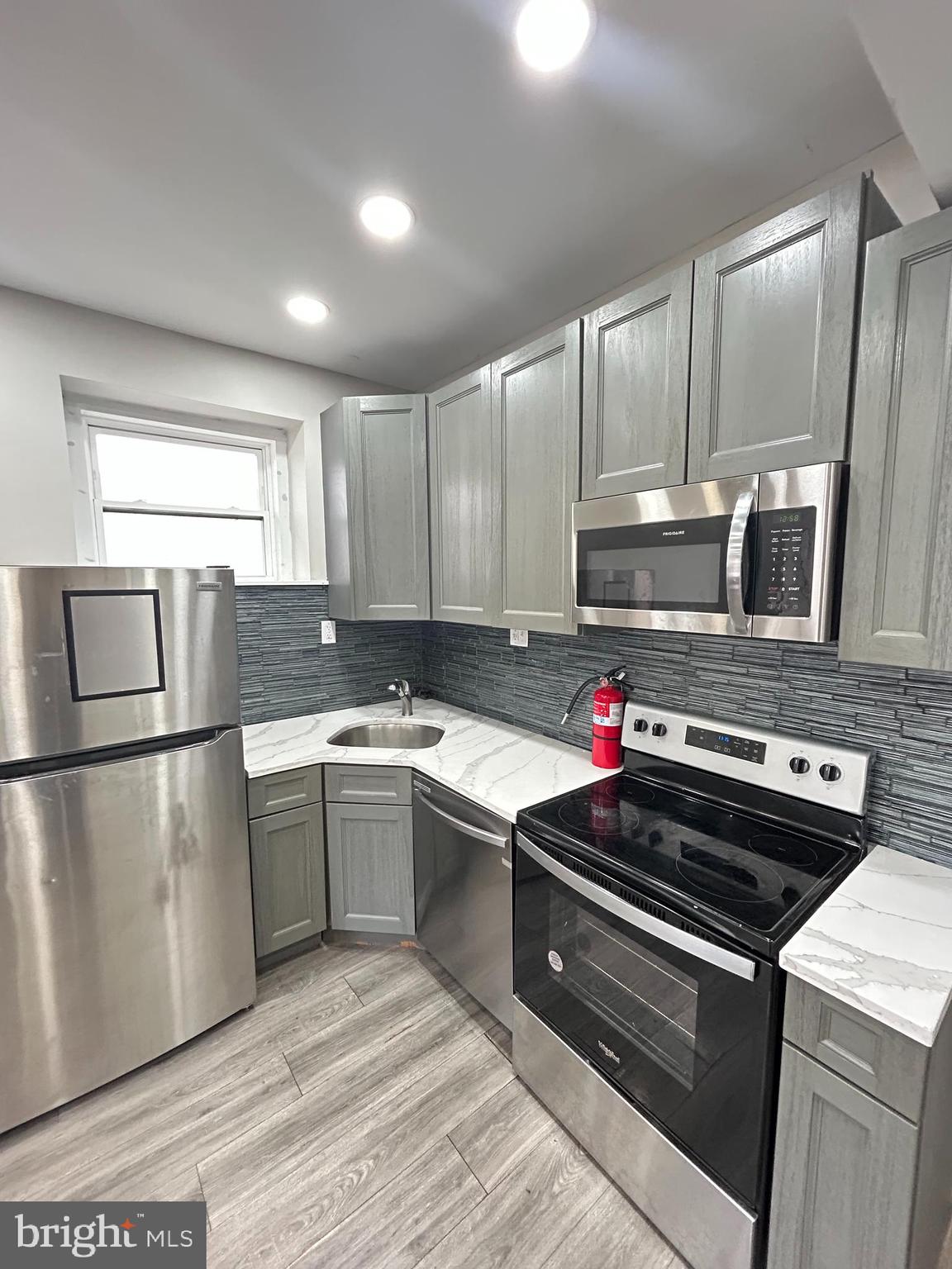 2417 North 54th Street, Unit D Philadelphia, PA 19131 - Photo 5 of 13 a kitchen with kitchen island granite countertop a sink stainless steel appliances and cabinets