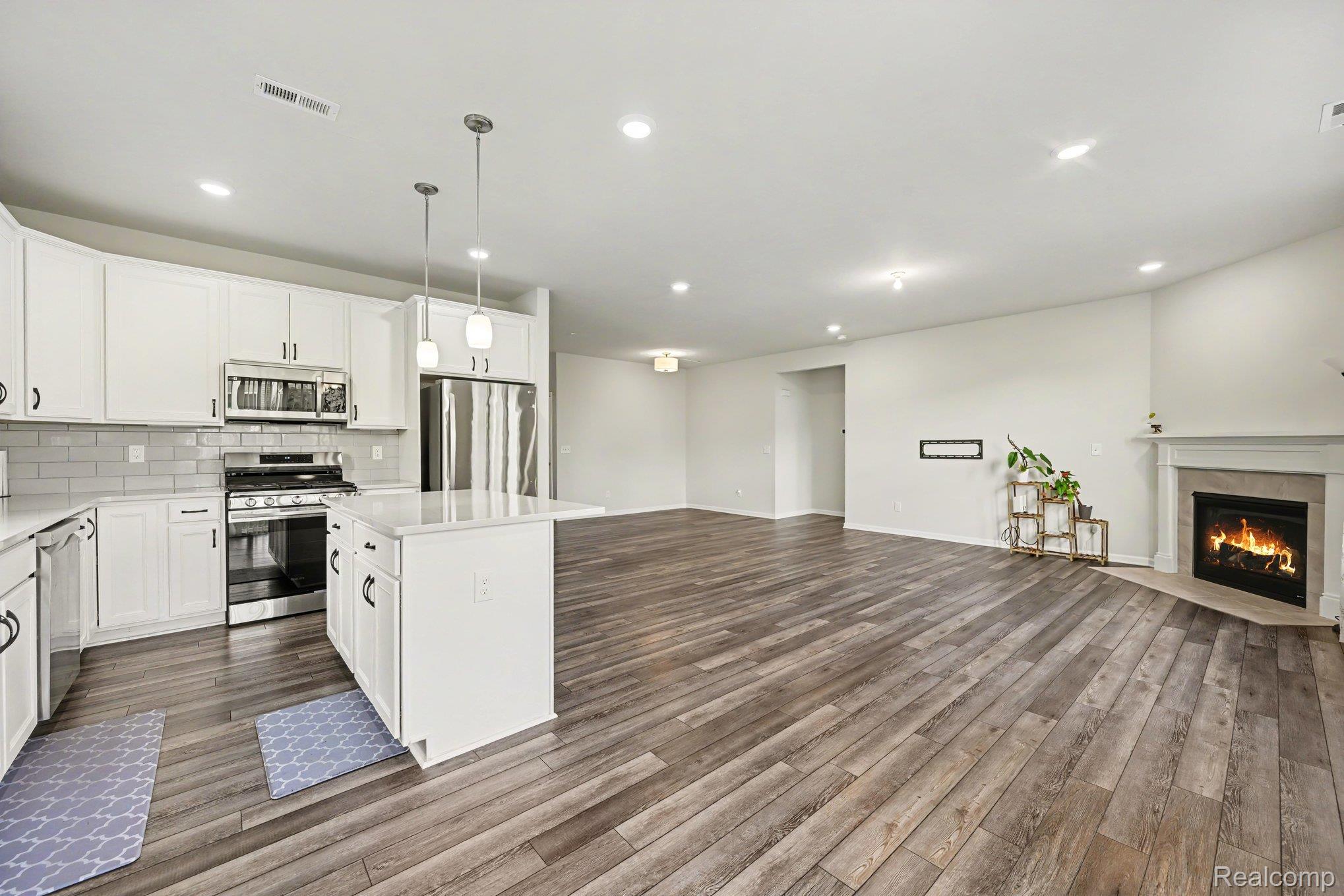 50153 Fowler Road Canton, MI 48188 - Photo 8 of 27 Open-concept living space with wood-finish flooring, a kitchen island, white cabinetry, and stainless steel appliances