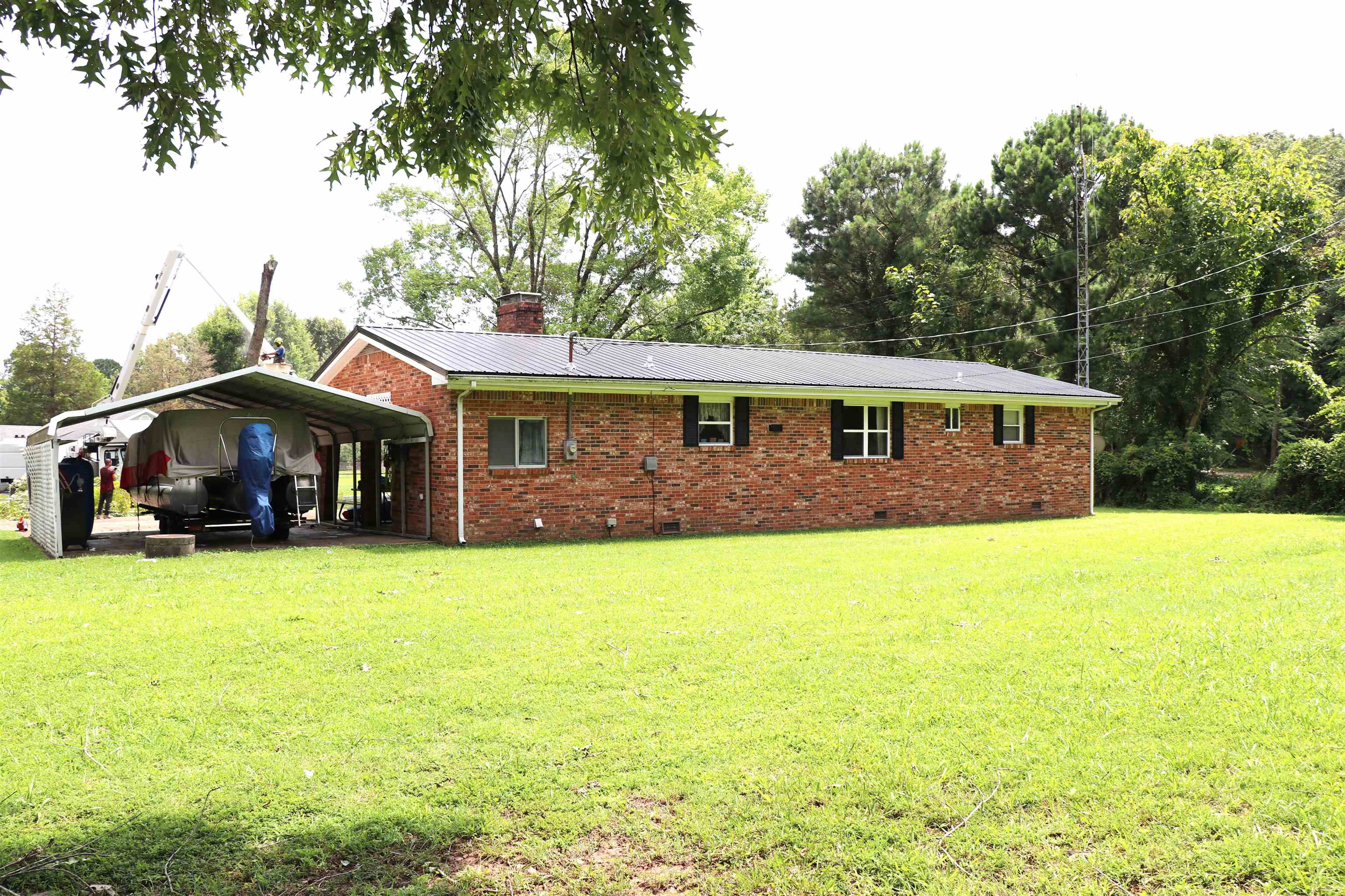 160 Patrick Drive Springville, TN 38256 - Photo 14 of 34 Brick exterior residence featuring a metal roof, attached carport, and multiple windows with dark shutters