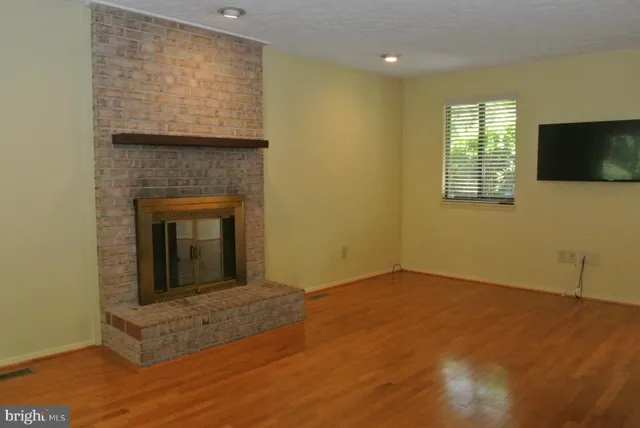 a view of an empty room with wooden floor and a fireplace
