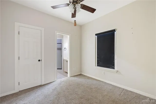 an empty room with a ceiling fan and a window