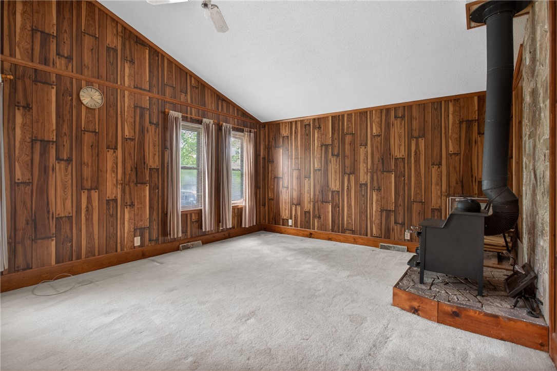 112 Holliday Lane Pendleton, SC 29670 - Photo 9 of 42 A rustic living area boasts a cozy wood-burning stove and rich wood paneling throughout.