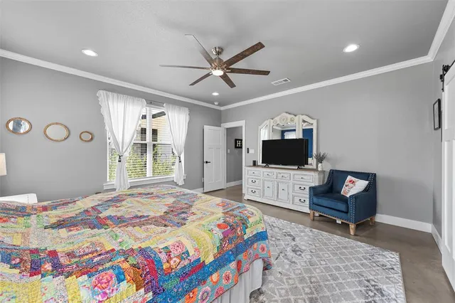 a bedroom with a bed a couch and a flat screen tv