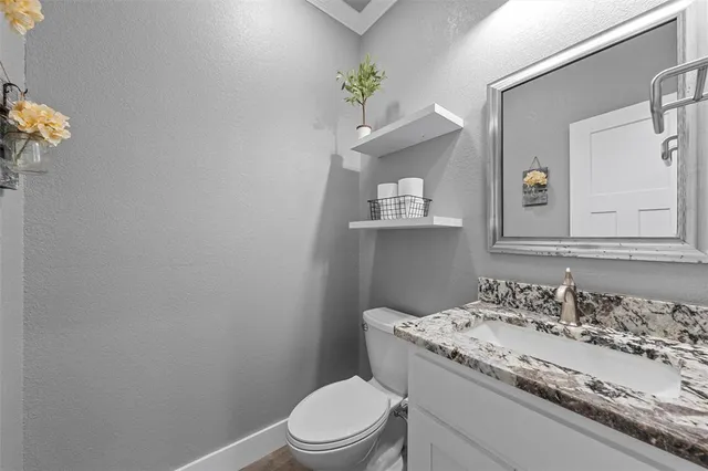 a bathroom with a granite countertop toilet sink and mirror