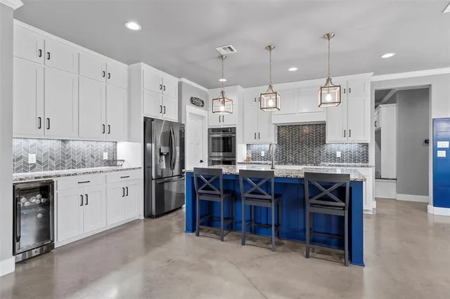 a large kitchen with granite countertop a sink cabinets and stainless steel appliances