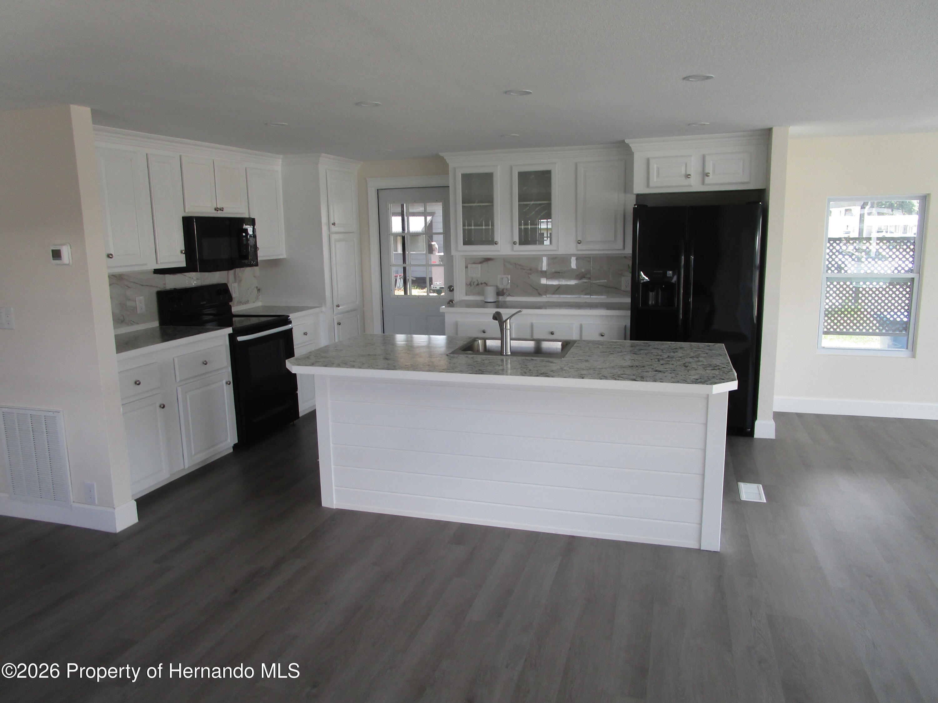14790 Rialto Avenue, Unit 3 Brooksville, FL 34613 - Photo 12 of 15 a large kitchen with stainless steel appliances a large counter top a stove a refrigerator a sink and dishwasher with wooden floor