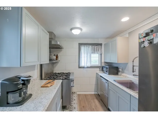 a kitchen with stainless steel appliances granite countertop a sink stove and refrigerator