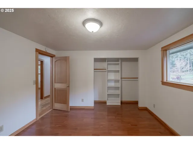 a view of empty room with wooden floor and closet