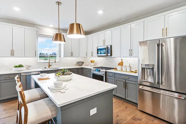 a kitchen with stainless steel appliances granite countertop a sink a stove a refrigerator cabinets a dining table and chairs