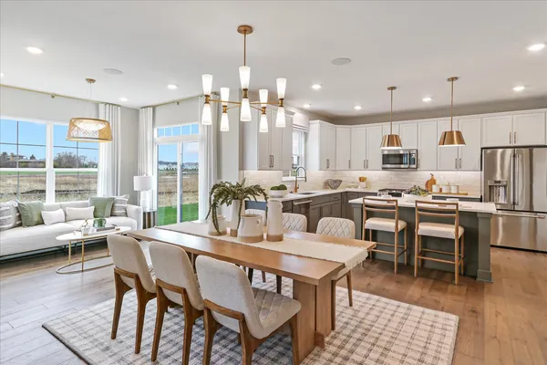 a dining room with stainless steel appliances kitchen island granite countertop a dining table chairs and view of living room