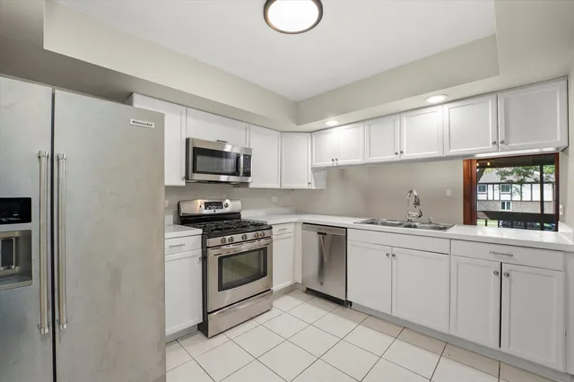 a kitchen with white cabinets appliances and a sink
