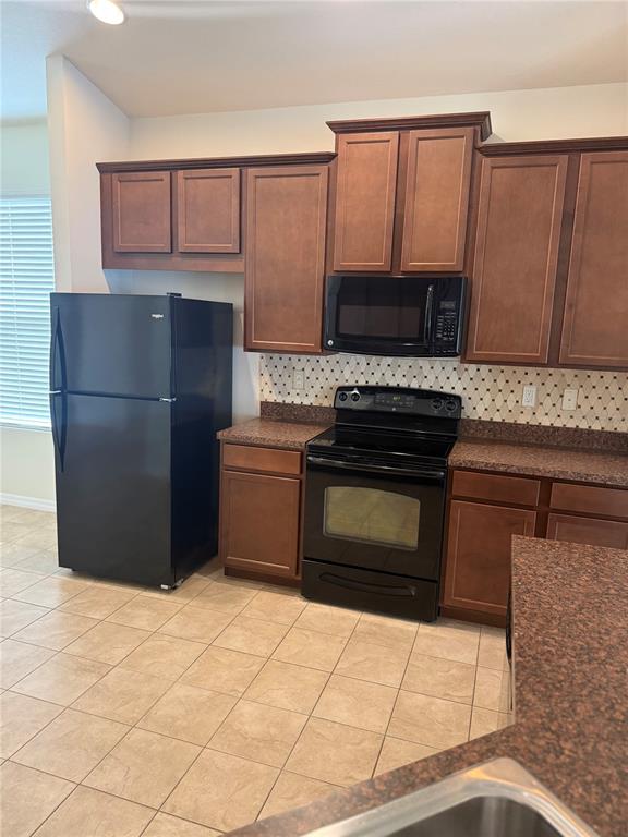 2862 Running Brook Circle Kissimmee, FL 34744 - Photo 8 of 24 a kitchen with granite countertop a stove top oven microwave and cabinets