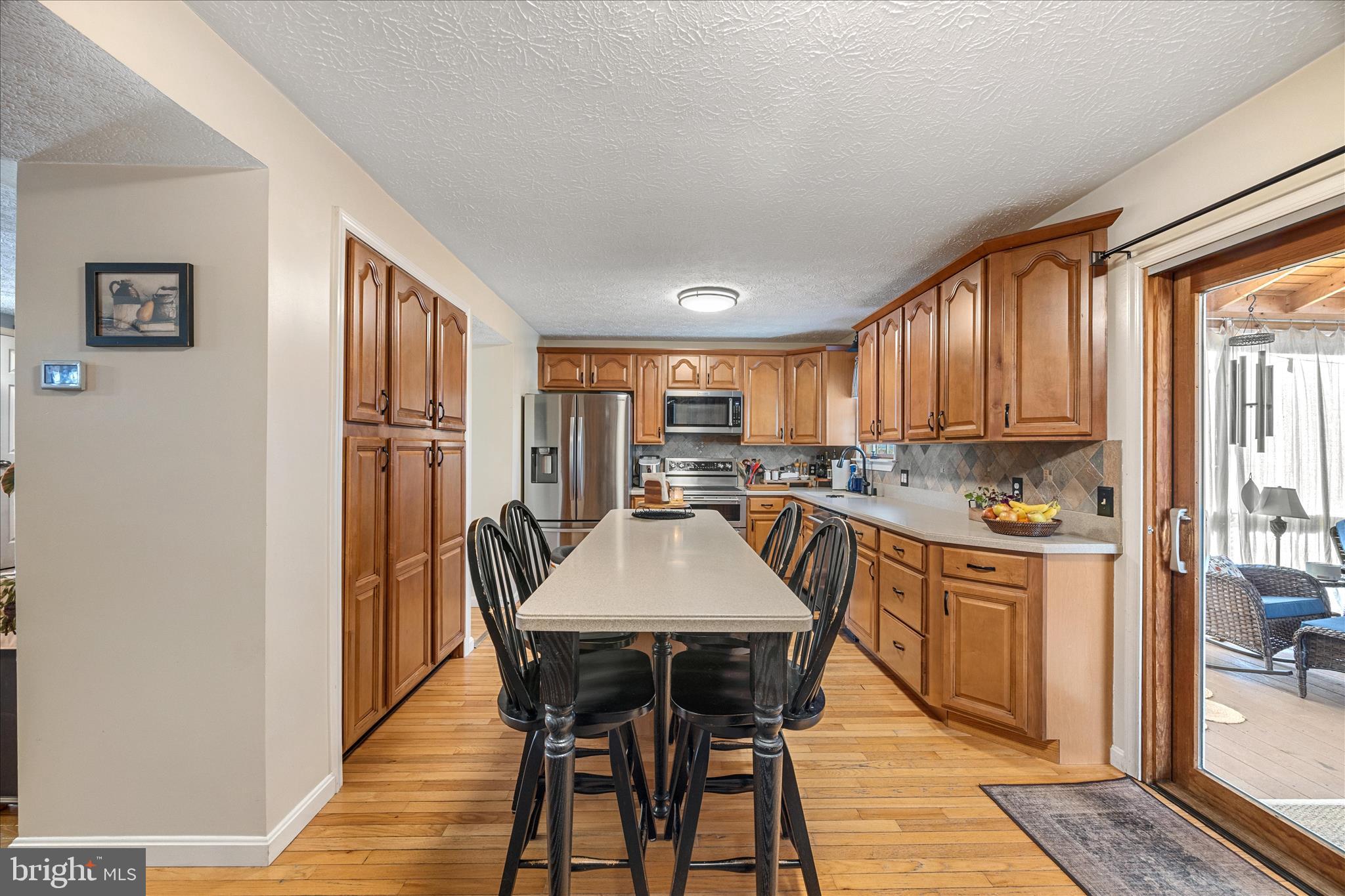 7914 Leeds Drive Pasadena, MD 21122 - Photo 13 of 49 a kitchen with stainless steel appliances granite countertop a stove a refrigerator a dining table and chairs with wooden floor