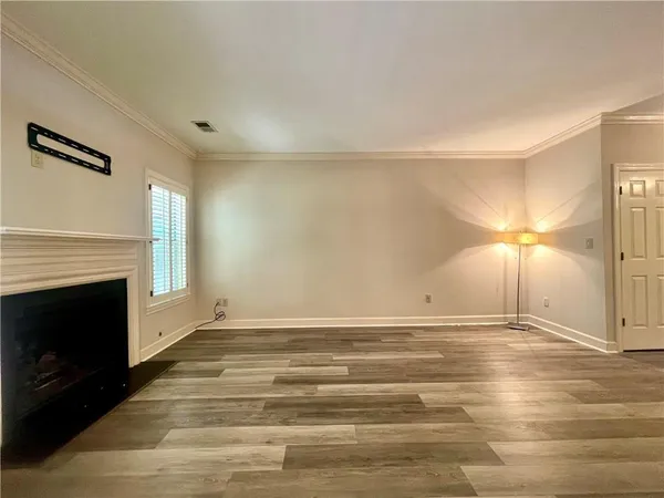 a view of an empty room with wooden floor fireplace and a window