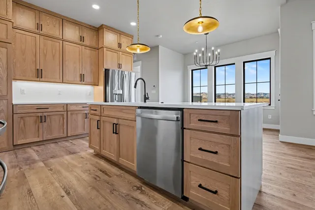a kitchen with stainless steel appliances granite countertop a sink cabinets and wooden floor