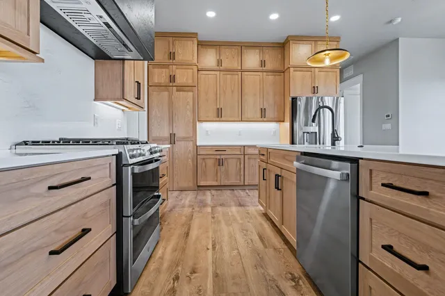 a kitchen with stainless steel appliances granite countertop a stove a sink dishwasher and a refrigerator