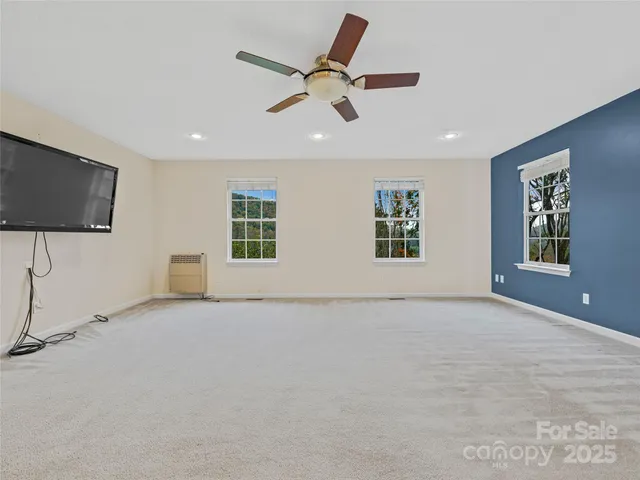 an empty room with windows and ceiling fan