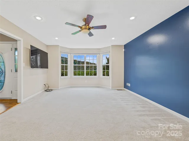 a view of an empty room with a window and a kitchen
