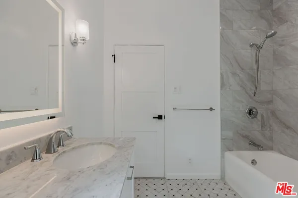 a bathroom with a granite countertop tub sink and mirror
