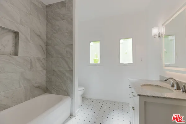 a bathroom with a granite countertop sink a toilet and bathtub