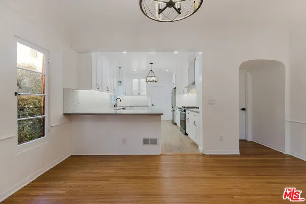 a view of kitchen and empty room with wooden floor