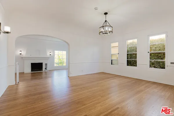 an empty room with wooden floor fireplace and windows