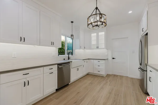 a kitchen with cabinets a sink dishwasher and a stove with wooden floor