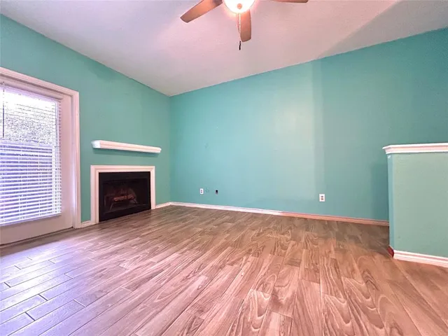 a view of empty room with wooden floor and fireplace