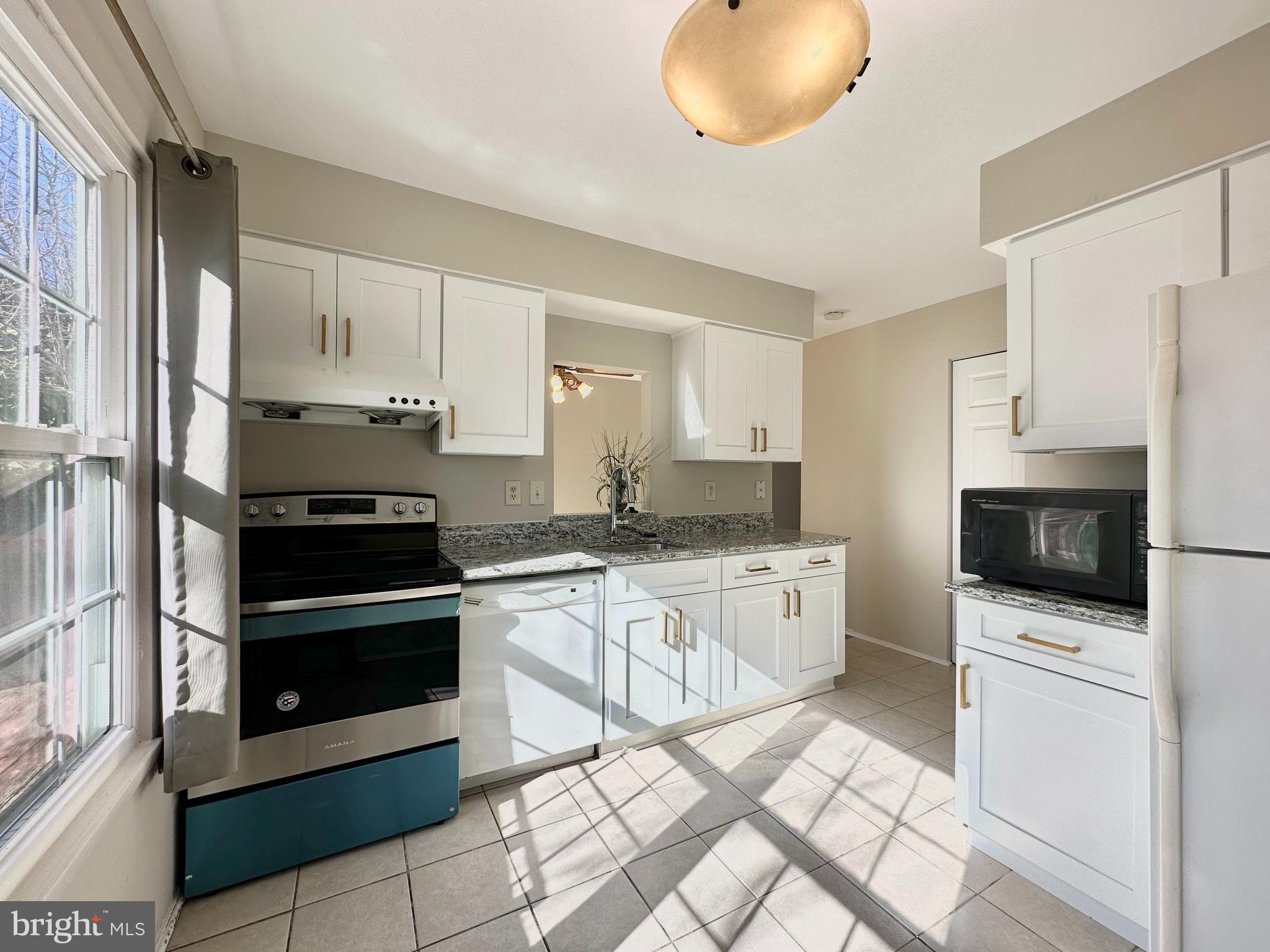 402 Carousel Court Gaithersburg, MD 20877 - Photo 9 of 29 a kitchen with stainless steel appliances kitchen island granite countertop a stove a sink and a microwave