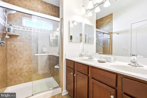 a bathroom with a double vanity sink mirror and shower