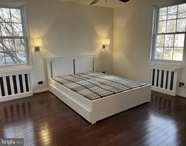 a spacious bedroom with a bed and wooden floor