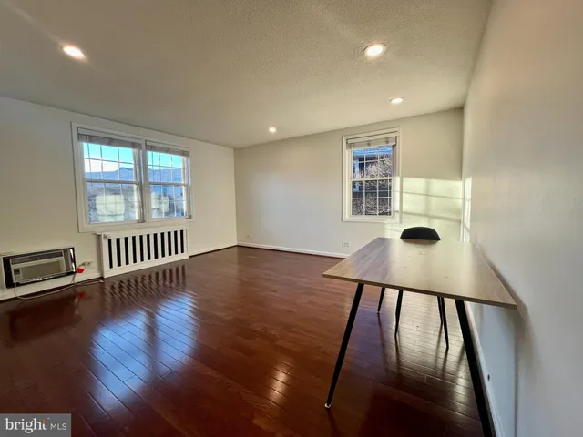 a view of an empty room with wooden floor and windows
