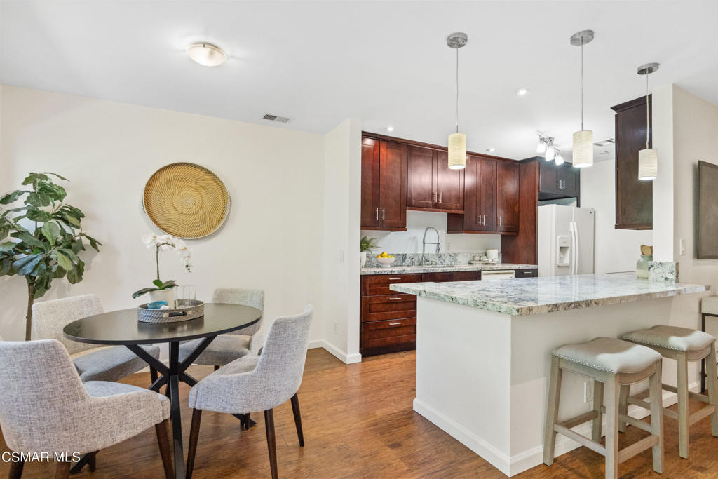 23637 Park Capri, Unit 36 Calabasas, CA 91302 - Photo 15 of 39 a kitchen with stainless steel appliances granite countertop a sink a stove a refrigerator a dining table and chairs with wooden floor